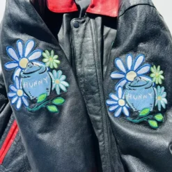 Close-up view of the sleeve of a vintage 90’s Winnie The Pooh & Friends leather jacket, showcasing detailed embroidery and premium stitching.