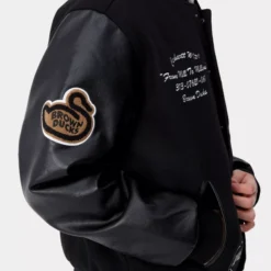 Detailed view of the right sleeve of the Carhartt WIP Brown Ducks Varsity Black Jacket, highlighting fabric and construction.