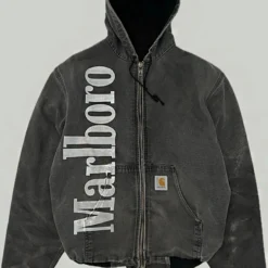 Vintage Marlboro Carhartt jacket in faded black with a zip-up front, hood, ribbed cuffs, and bold white Marlboro branding on the left side.