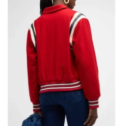 A person wearing the Mother The Team Spirit Varsity Jacket in red, showcasing striped shoulder details and ribbed hem.