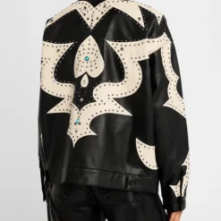 The back view of the Mother The Zip It Studded Leather Jacket, showcasing bold Western-style beige paneling, silver stud accents, and turquoise embellishments on a black leather base.
