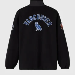Black NHL Vancouver Canucks Coach’s Jacket featuring bold "VANCOUVER" text, an OVO owl logo, and embroidered sleeve patches.