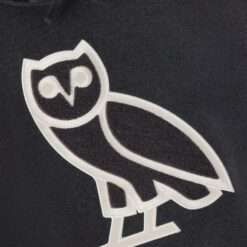 Close-up of the embroidered OVO owl logo on a charcoal hoodie.