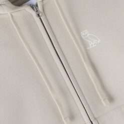 Close-up of the embroidered OVO owl logo on beige Relaxed-fit Full-Zip Hoodie.