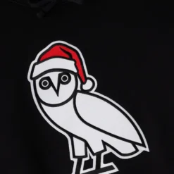 Close-up of the OVO owl logo with a Santa hat on a black hoodie.