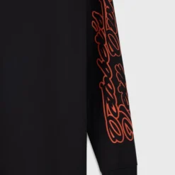 A detailed view of the OVO Sports Script T-shirt sleeve, showcasing the intricate script design in contrasting red.