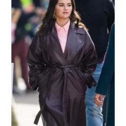 Selena Gomez wearing a long, dark brown leather trench coat with a belted waist in Only Murders in the Building Season 3.