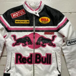 A stylish Redbull women's bomber jacket in white, pink, and black, featuring a front zipper, multiple brand patches, and a bold Red Bull logo with two black bulls on the chest.
