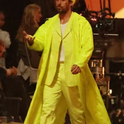 Ryan Gosling wearing a vibrant yellow long coat with a matching outfit, exuding bold and stylish energy on a movie set.
