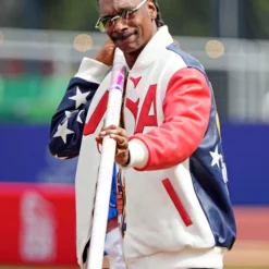 Side view of Snoop Dogg wearing a U.S. Olympic 2024 bomber jacket, showcasing star-spangled sleeve details.