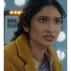 Varada Sethu wearing a golden yellow trench coat from Doctor Who Season 15 – eye-catching women's outerwear featuring a long tailored silhouette, wide lapels, and belted waist.